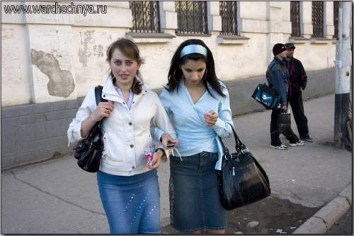 Young women wear denim skirts and carry black leather han...