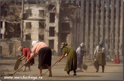Women sweep and shovel debris from the streets in Grozny,...